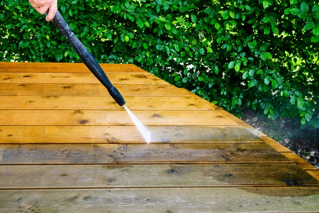 A wood deck is being power washed