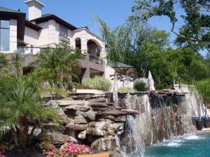 high-end backyard landscape with waterfall into pool