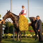 Winning horse and jockey with blanket of flowers at the Preakness Stakes